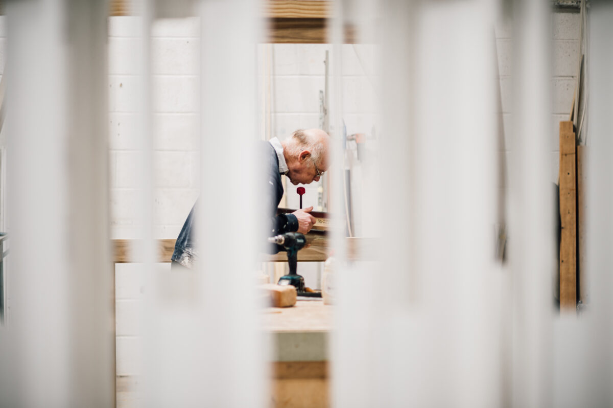 A member of the Tucker Joinery team works on the finer details of a timber project through frames from the spray shop.