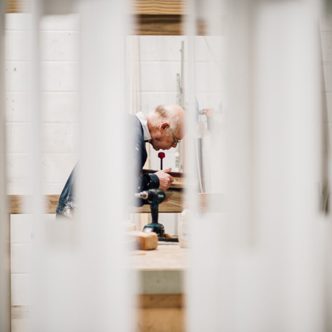 A member of the Tucker Joinery team works on the finer details of a timber project through frames from the spray shop.