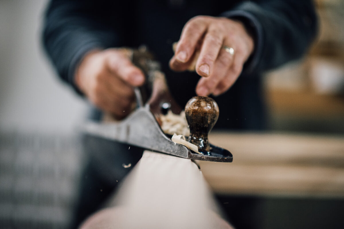 A close-up of a member of the Tucker Joinery team planing wood in the workshop.