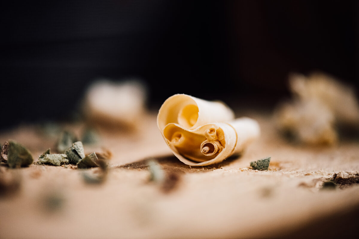 A close-up of a curled wood shaving on a workbench at the Tucker Joinery workshop.