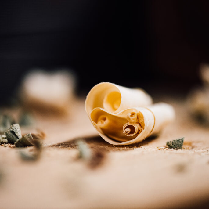 A close-up of a curled wood shaving on a workbench at the Tucker Joinery workshop.