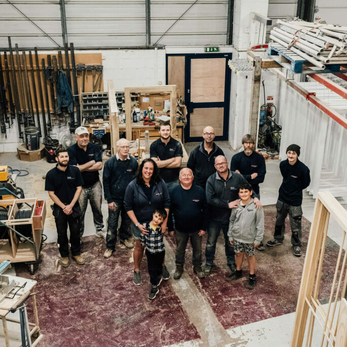 A top-down photo of the Tucker Joinery Team stood together in the workshop.