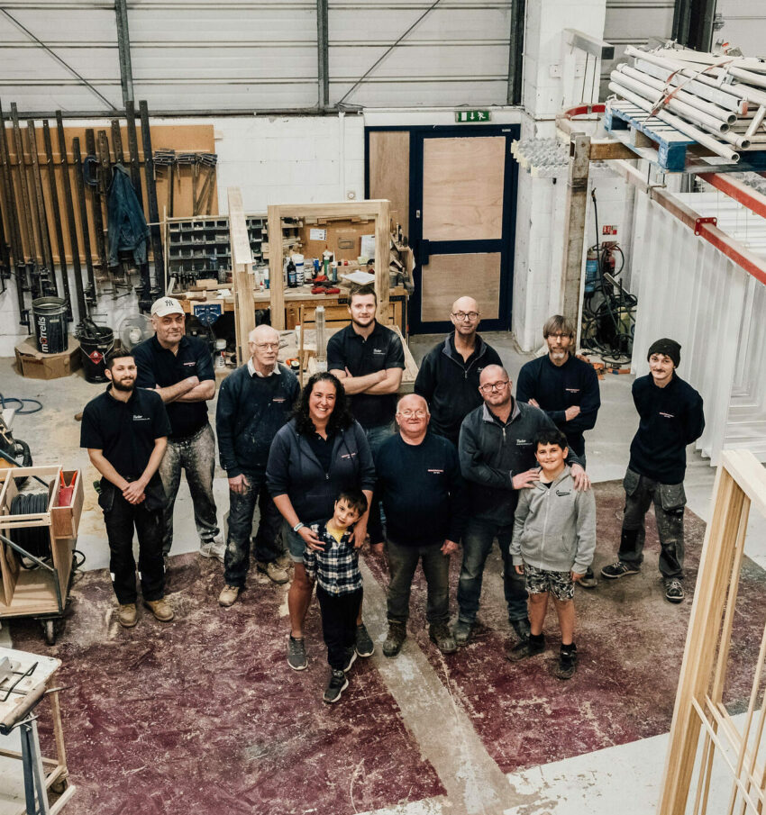 A top-down photo of the Tucker Joinery Team stood together in the workshop.