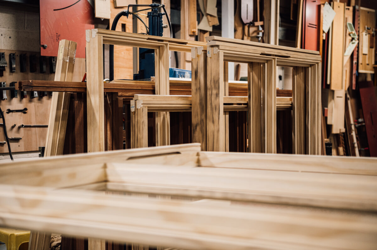 Several timber frames for windows or cabinets lean against the back wall of the Tucker Joinery workshop.