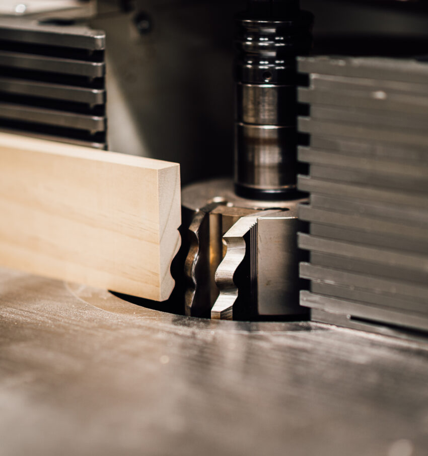 A close up of timber mouldings being shaped and cut with a machine into an elegant shape, the Tucker Joinery workshop (Andover).