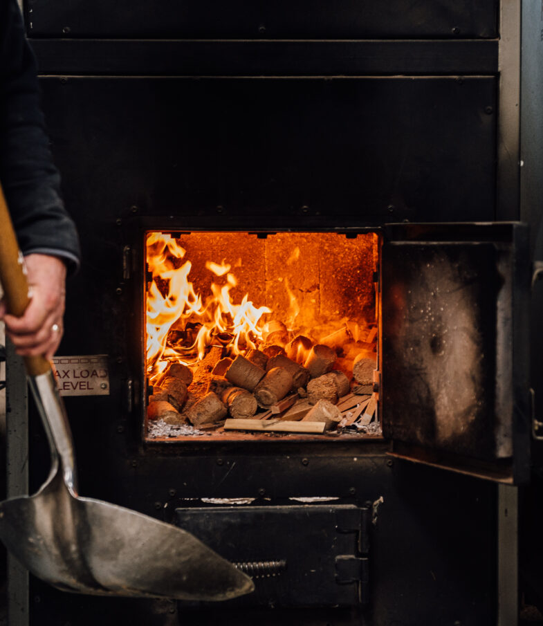 A pile of wood burner briquettes burns in an open fireplace, at the Tucker Joinery workshop.