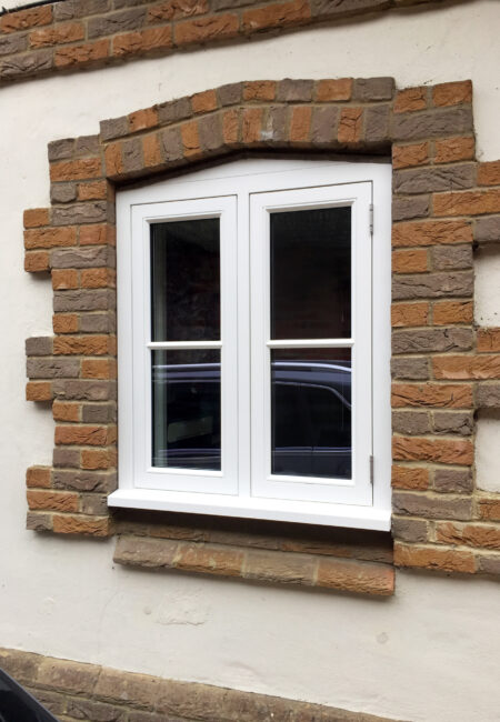A bespoke window frame finished with white paint and set in a brick surround. Tucker Joinery, based in Andover.