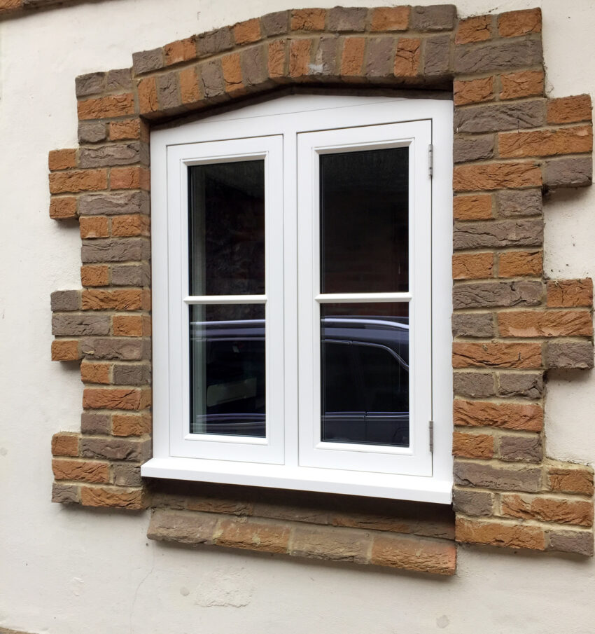 A bespoke window frame finished with white paint and set in a brick surround. Tucker Joinery, based in Andover.