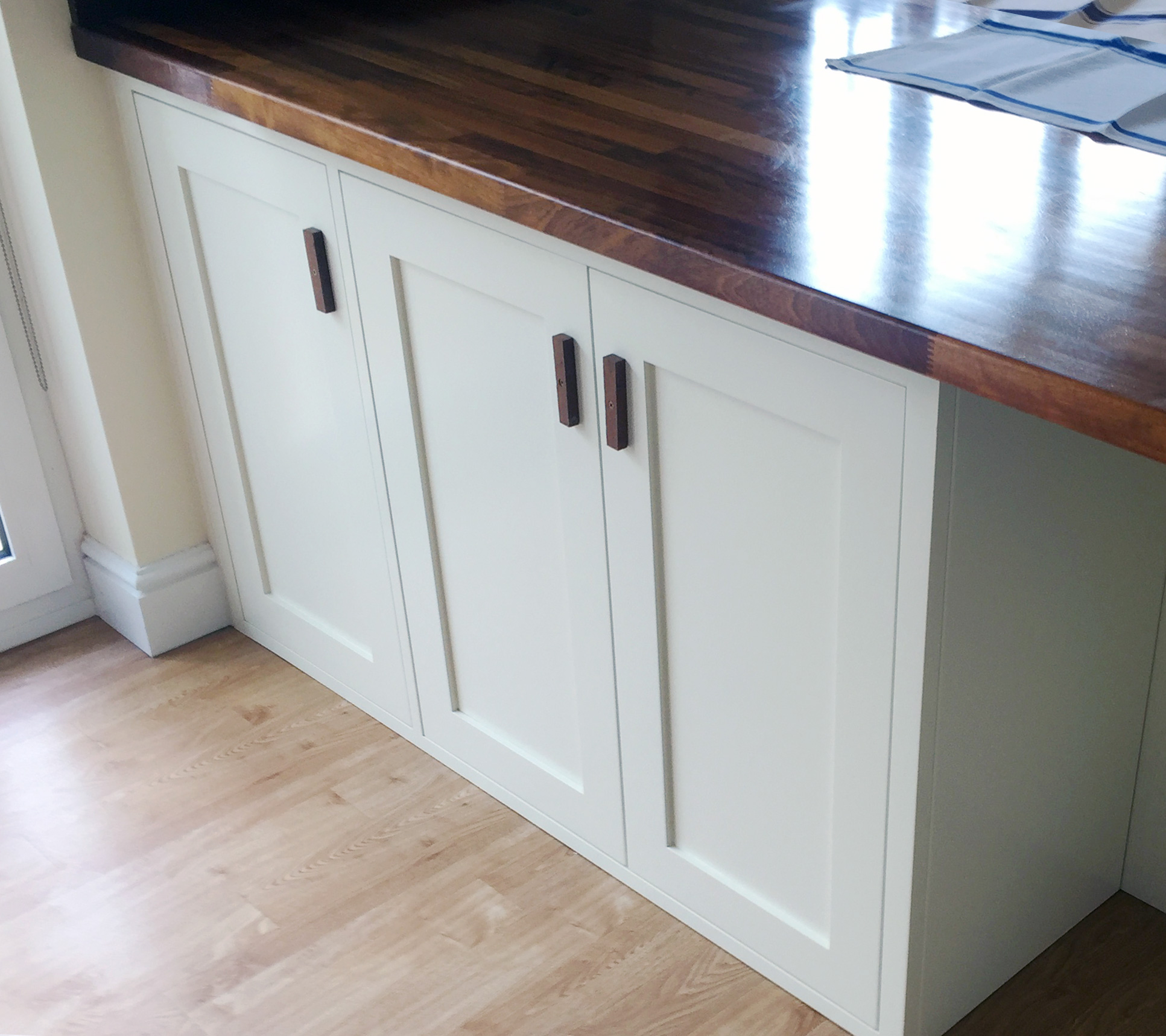 Bespoke kitchen cabinets sprayed white and finished with dark wood handles, designed, built, and installed by Tucker Joinery, Andover.